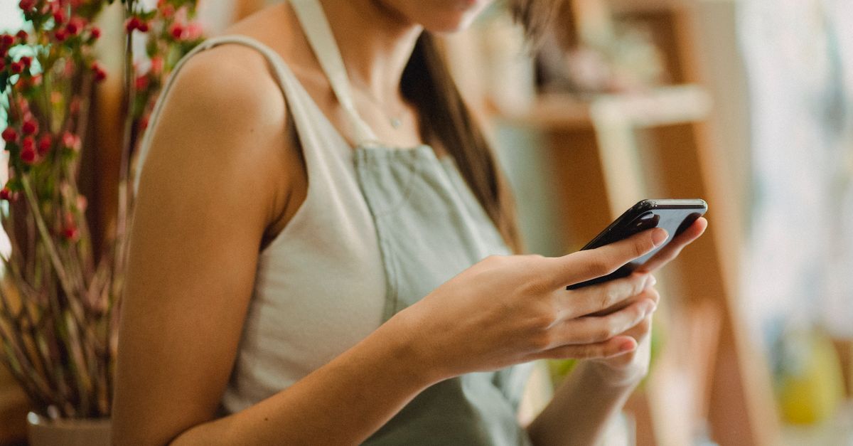 Dueño de un negocio local consultando mensajes de WhatsApp en su móvil sobre el mostrador